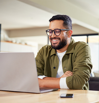Man smiling with arms folded in front of laptop