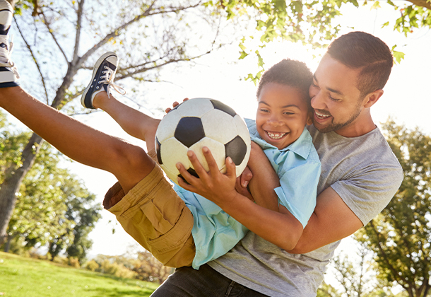 Father and son playing soccer outdoors