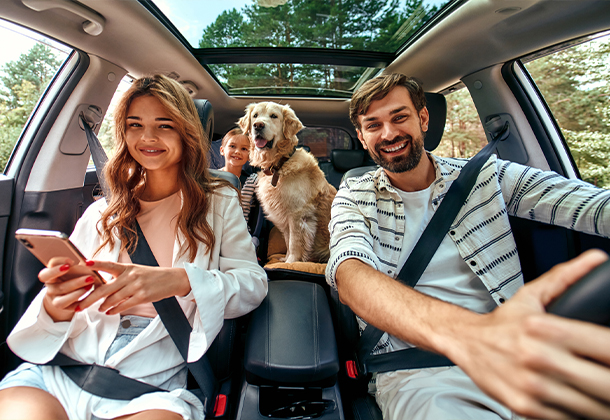 Family of three driving in a car with child and dog in the backseat