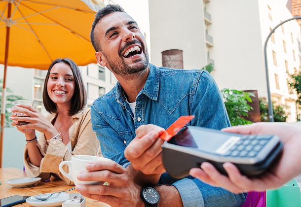 Woman and man smiling and paying for coffee with credit card