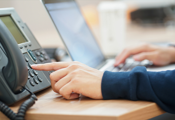 person ready to dial phone while in front of laptop