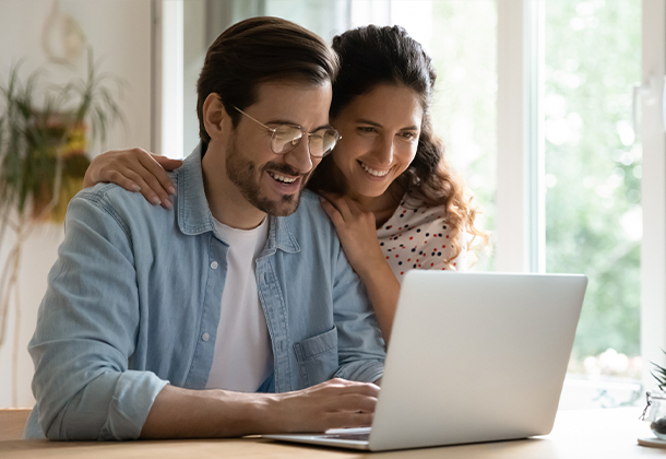 Two people in front of laptop screen smiling