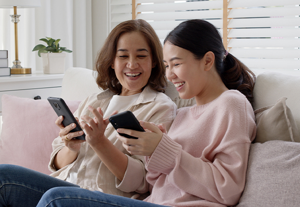 Two people sitting on couch looking at cell phones