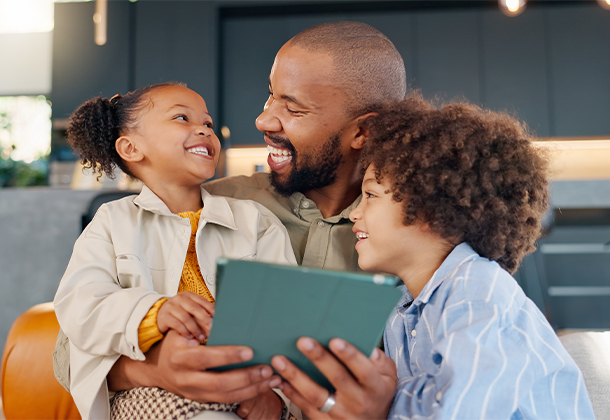Dad holding two daughters and tablet