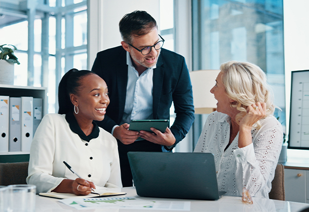 Three business people in meeting with a tablet, notebook, and laptop