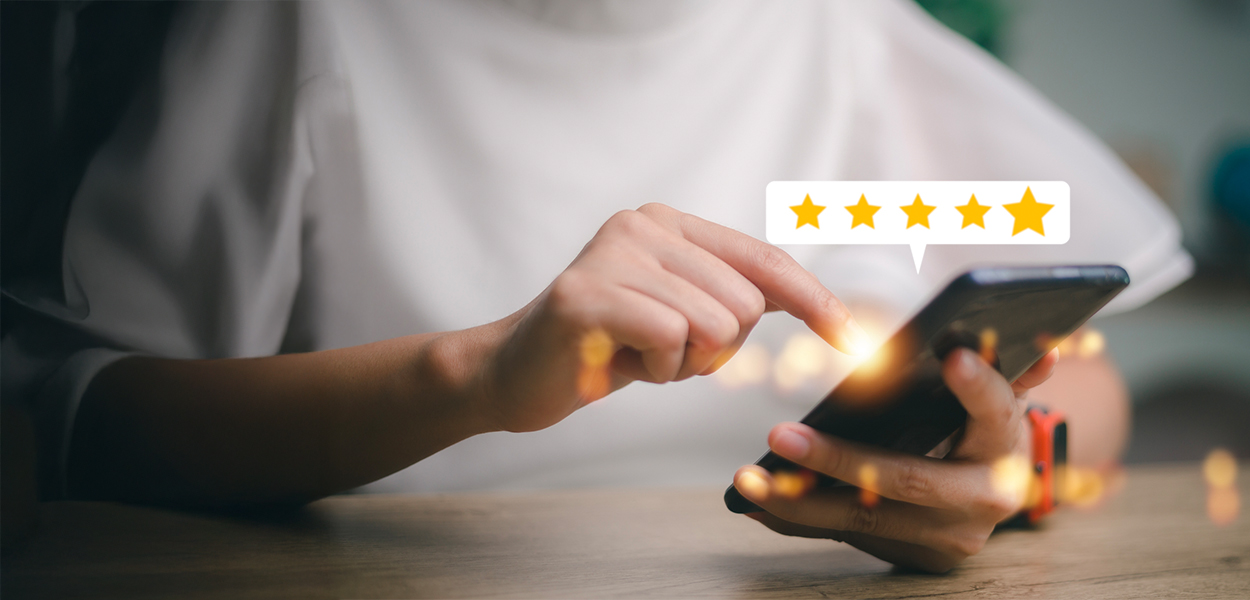 Person holding cell phone with five gold star review
