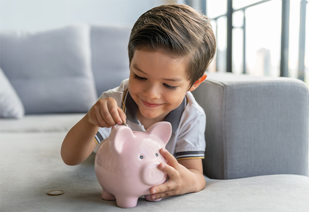 child putting money into piggy bank