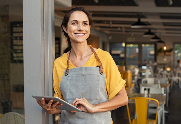 person at business with apron typing on tablet