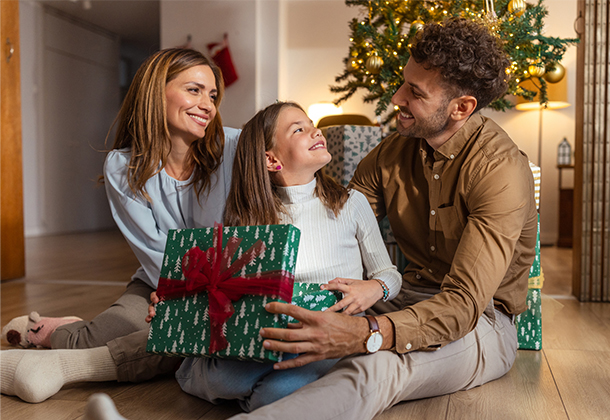 family holding a present under holiday decor